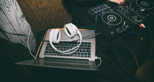 dj音乐网收录的车载DJ专区混音师在录音室调音台前工作，周围摆满了低音音箱